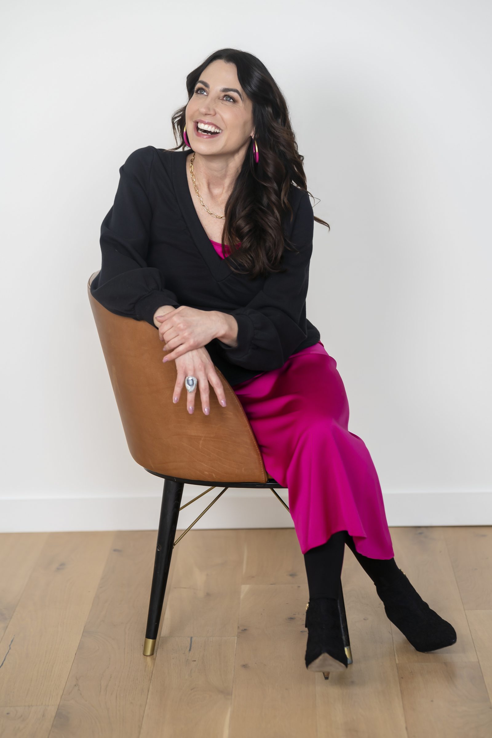Susan Page laughing in a cognac leather chair